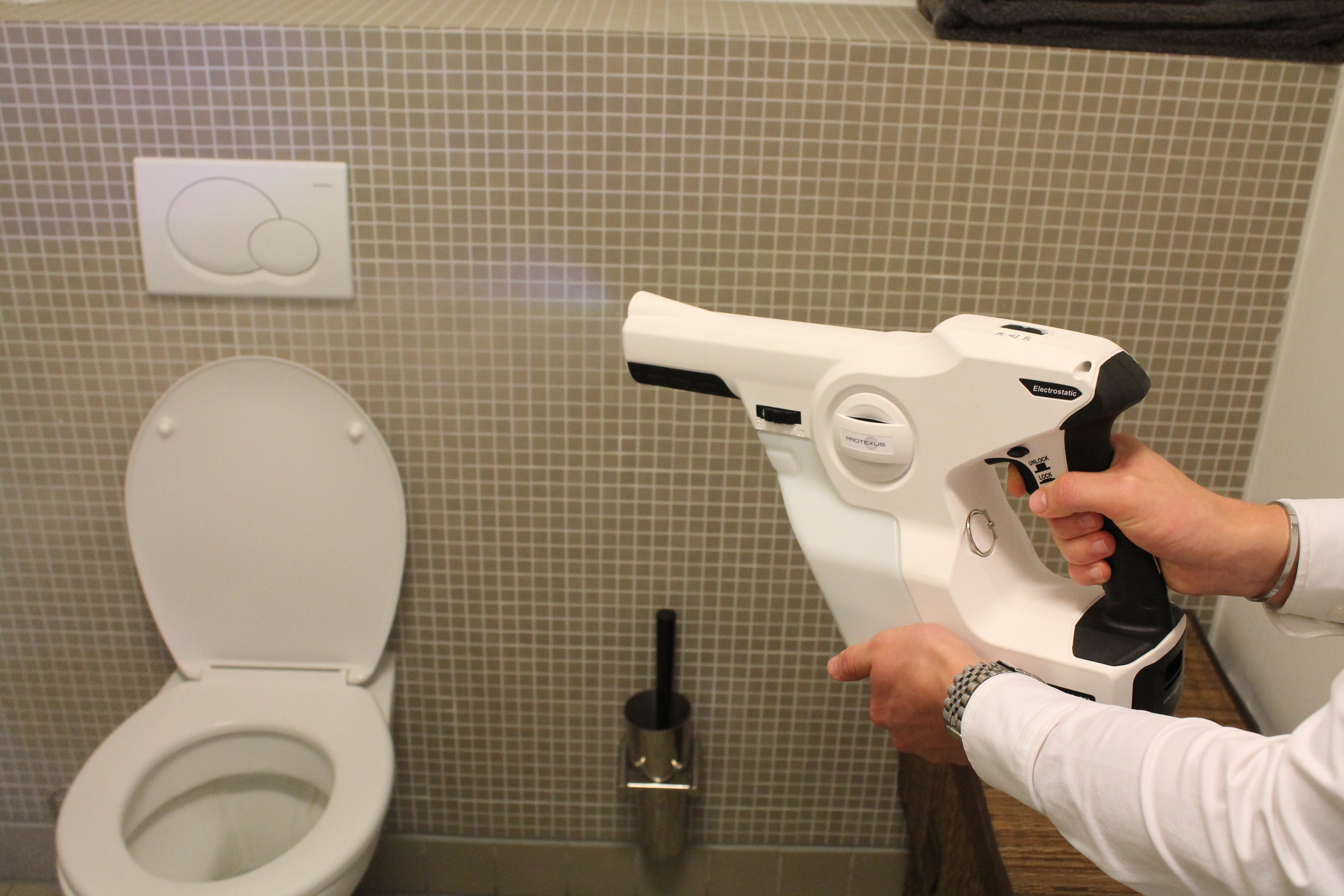 Billeder af protexus elektrostatisk sprayer, som anvendes på et toilet. På billedet kan man se at der kommer væske ud af dysen som har kurs mod toilettet.